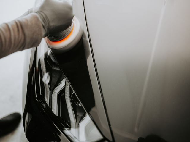 Close-up of a machine polisher head working a dark painted panel