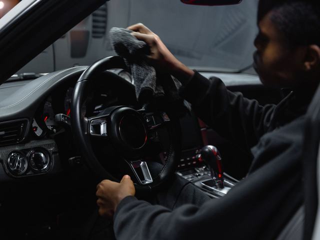A cloth being worked around a car's steering wheel and dash