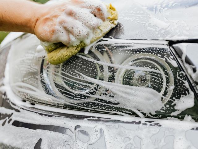 A sponge and suds being worked over a car headlight